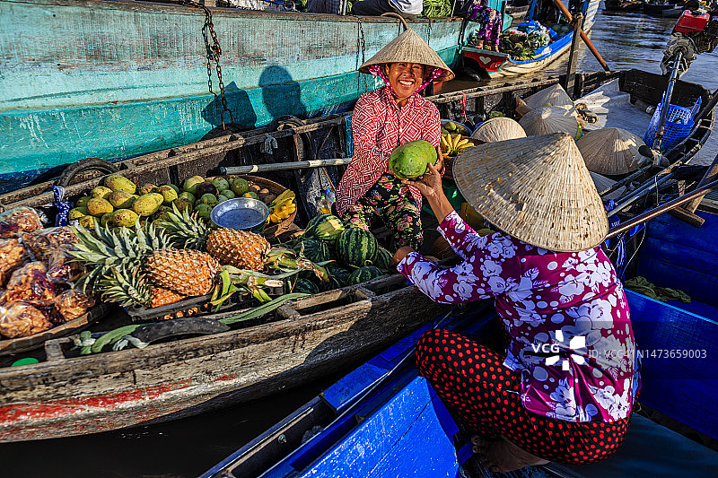 在越南湄公河三角洲水上市场卖水果的越南妇女图片素材