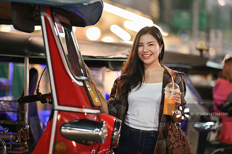 美丽的女性旅行者站在泰国夜市的嘟嘟车旁，旅行生活方式假期概念图片素材