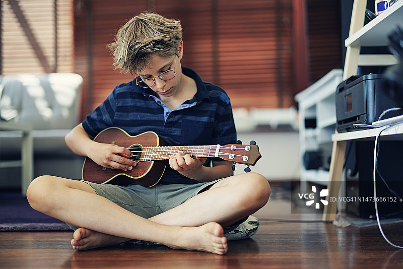 小男孩在家弹尤克里里图片素材