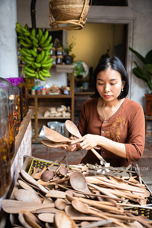 在越南出售自制木勺的年轻女子图片素材