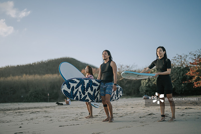 兴奋快乐的华裔冲浪者站在海滩边看着大海图片素材