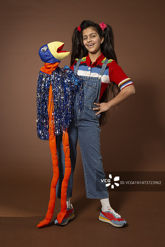 手持木偶，叉腰站立的女孩肖像图片素材