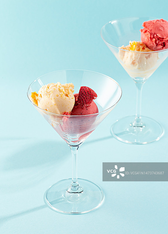 蓝色背景下鸡尾酒杯中的两勺水果冰沙图片素材