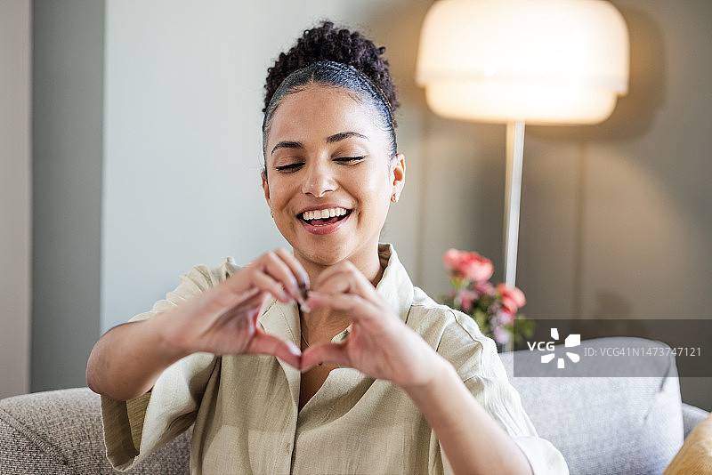 一位混合种族女性用她的手做成一个心形，表达爱意图片素材