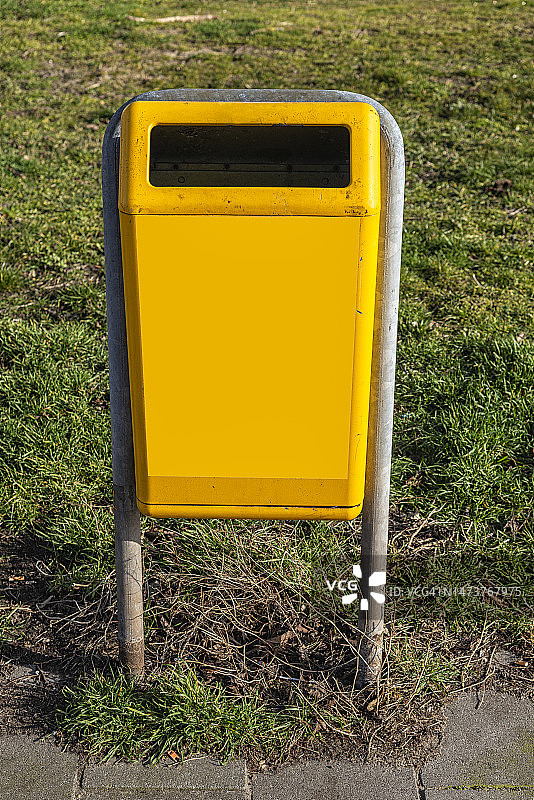 固定在金属U型管上的黄色户外垃圾箱图片素材