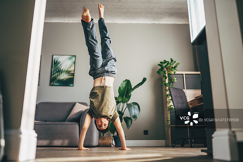 小男孩在家练习瑜伽、伸展、健身。远程在线教育培训，在家有氧运动。健康生活方式，新冠疫情，居家隔离。儿童居家运动。图片素材