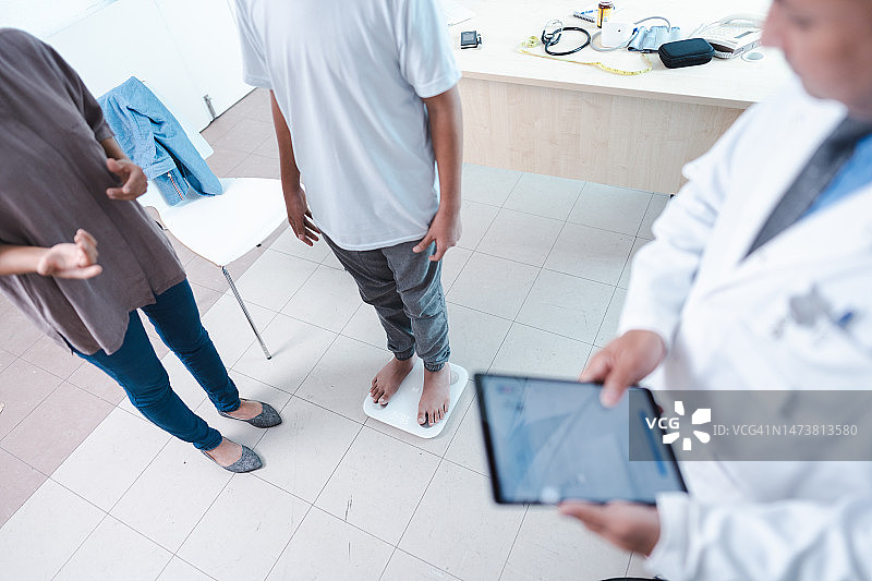 医生在检查男孩体重时使用平板电脑图片素材