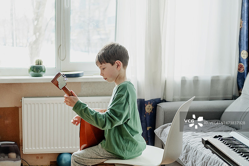 少年在家中窗边演奏巴拉莱卡琴图片素材