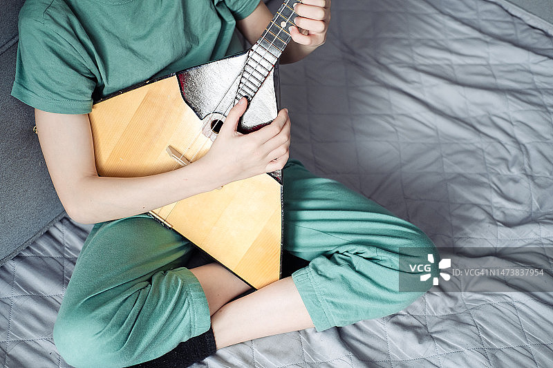 青少年在家里的沙发上弹奏巴拉莱卡琴图片素材