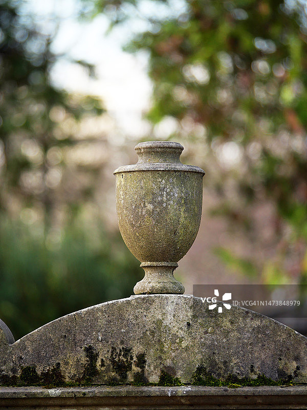 巴黎拉雪兹公墓中废弃坟墓顶部的风化石制骨灰瓮图片素材