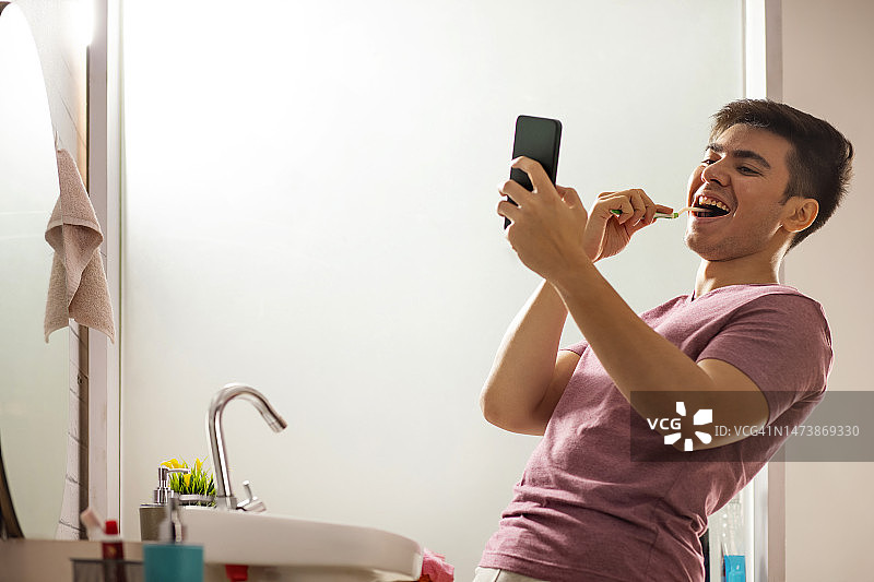 年轻男人在浴室刷牙时进行视频通话图片素材