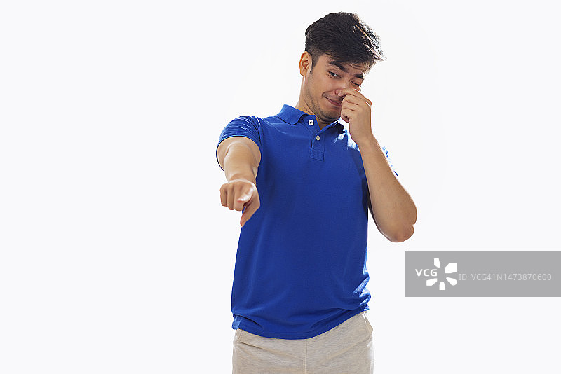 年轻男人因难闻气味捂住鼻子，白色背景图片素材