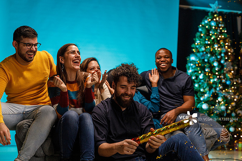 当他们的朋友燃放五彩纸屑时，快乐的人们做出反应并玩得开心图片素材