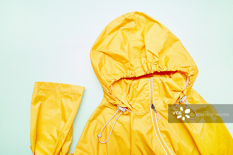 青绿色背景上的橙色带帽雨衣图片素材