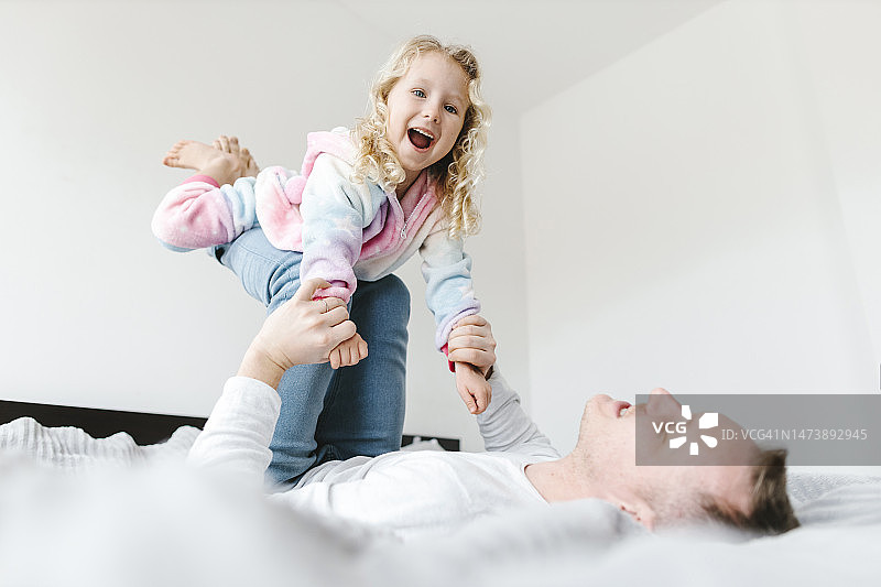 快乐的女儿在家里的床上和父亲玩耍图片素材