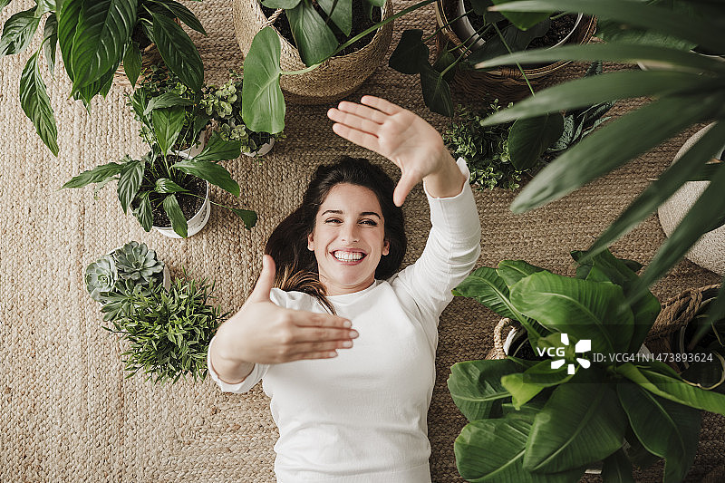 快乐的女人在地毯上用手指比心图片素材