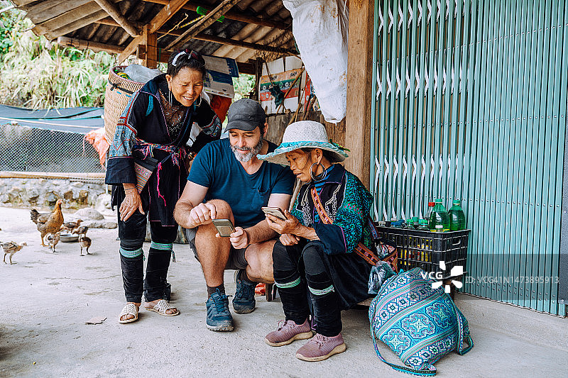游客向当地妇女展示手机上的照片图片素材