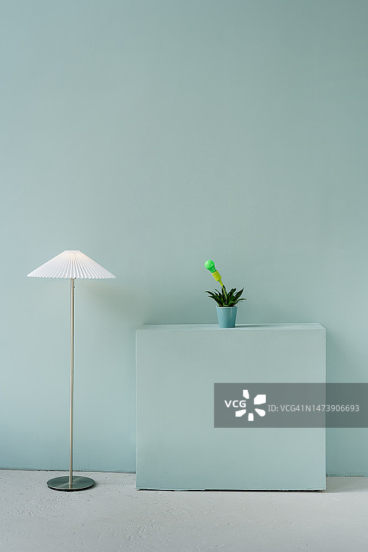 蓝色墙壁前的落地灯和绿植图片素材