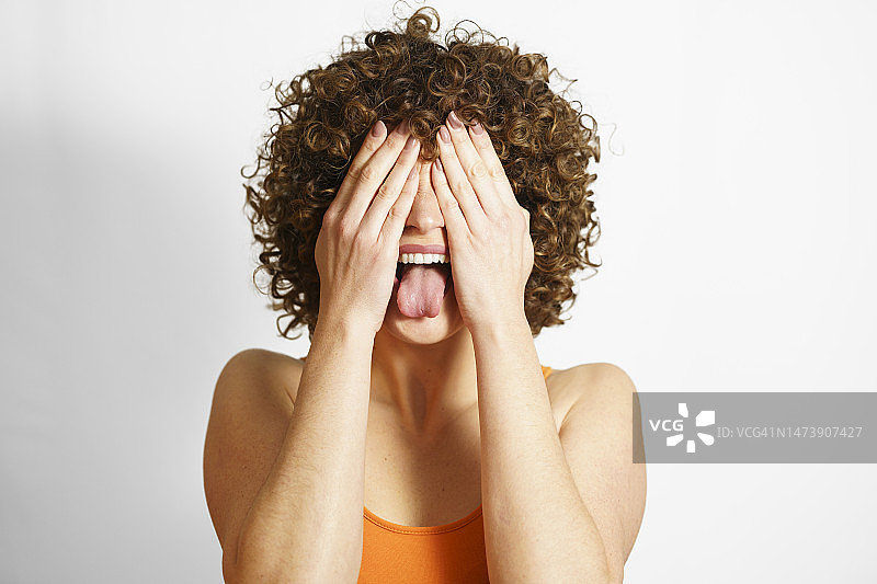 女人用手遮住脸并伸出舌头图片素材