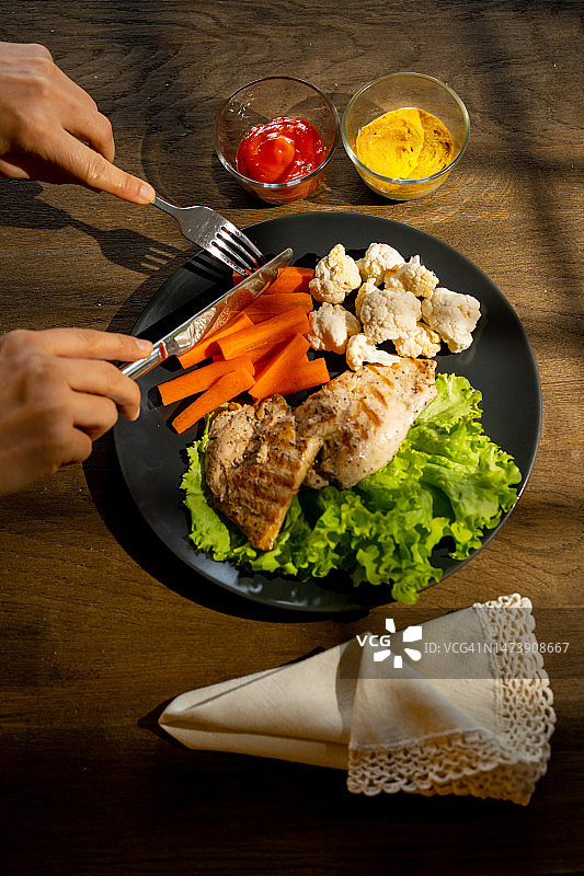 一位女士正在吃蔬菜和鸡肉图片素材