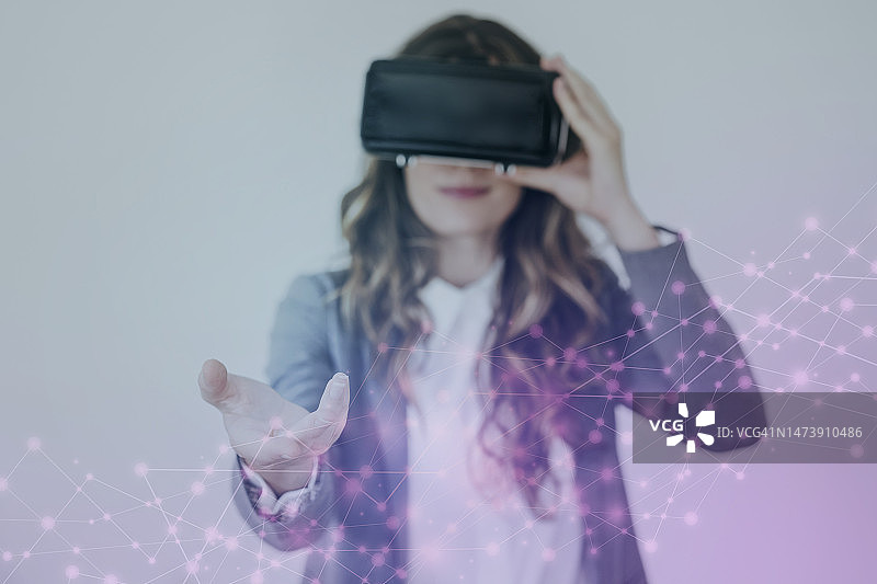 年轻女商人佩戴VR眼镜在办公室做手势图片素材