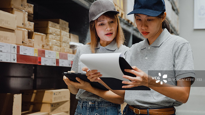 亚洲女工人在仓库用平板电脑检查库存图片素材