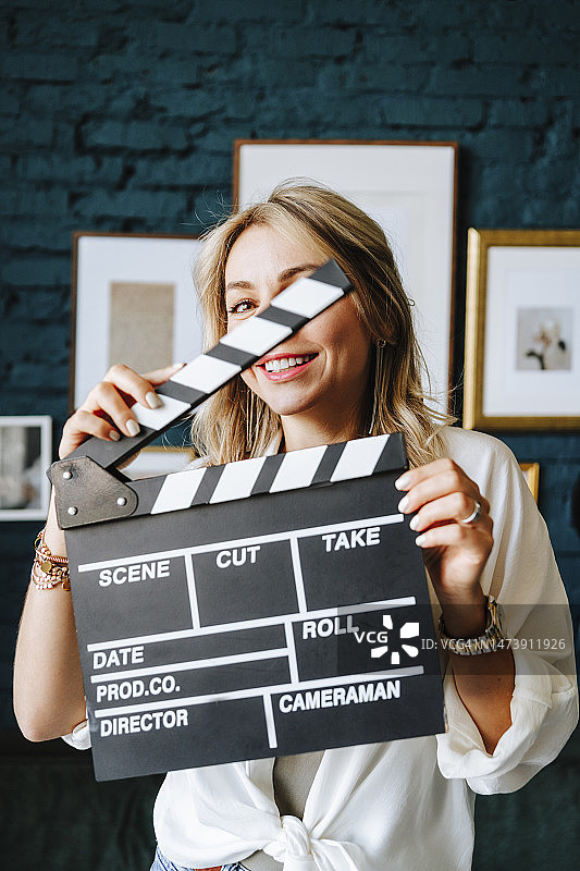 微笑的女演员在片场拿着场记板图片素材