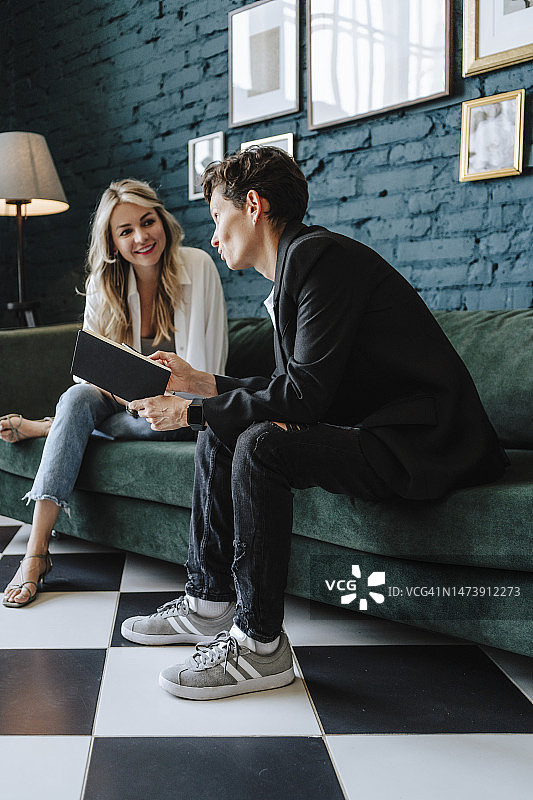 在电影拍摄现场，微笑的女演员与制片人坐在沙发上交谈图片素材