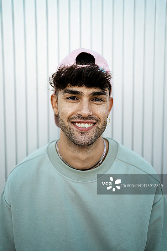 戴着帽子的快乐年轻人站在墙前图片素材