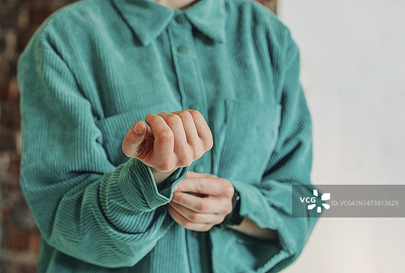 女人在扣绿色衬衫的袖扣图片素材