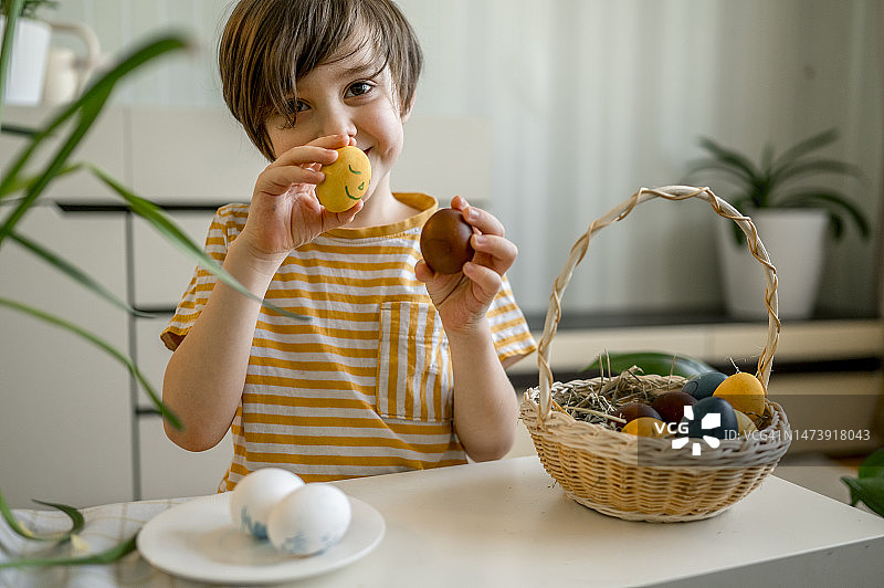 在家手拿复活节彩蛋的微笑男孩图片素材