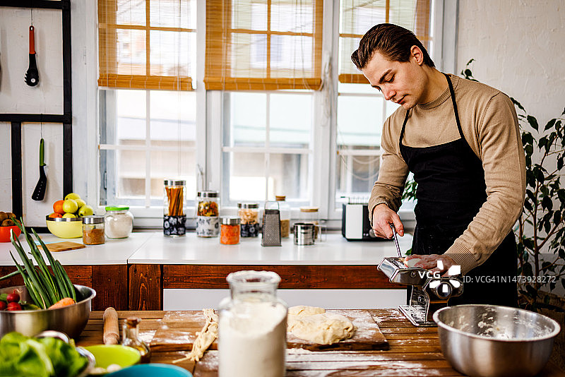 用滚动机制作自制意大利面的年轻男子图片素材