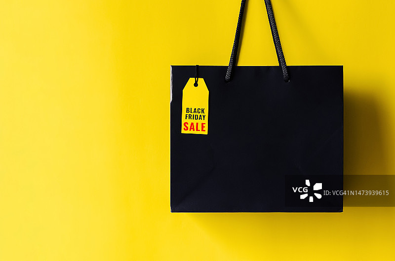 黑色星期五购物概念：带有价格标签的黄色背景购物袋图片素材