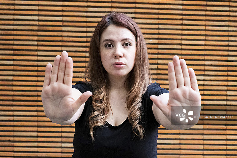 年轻的白人拉丁裔女子看着镜头，用双手做出停止的手势图片素材