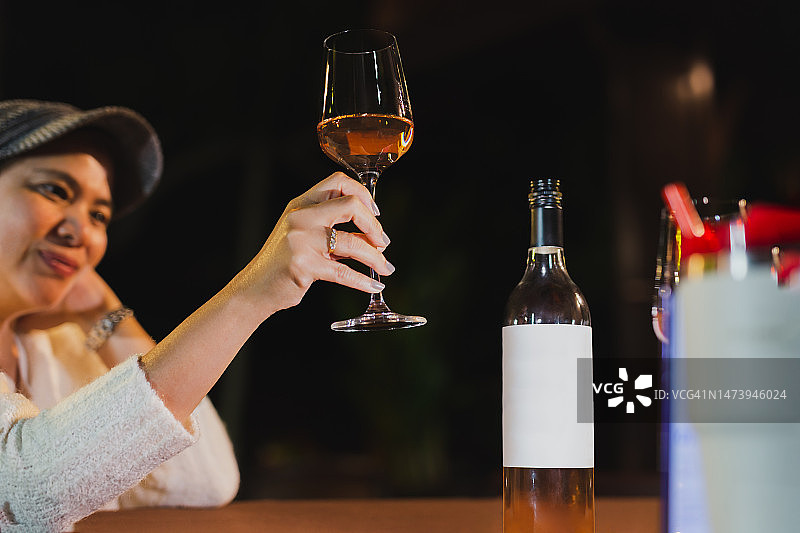 在泰国餐厅放松，拿着一杯酒的快乐女人图片素材