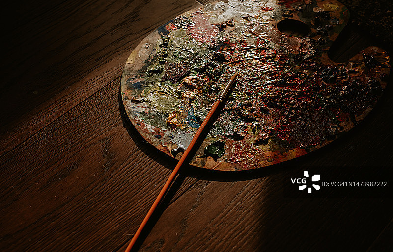 艺术家油漆调色板上覆盖着各种颜色的油漆，画笔放在上面图片素材
