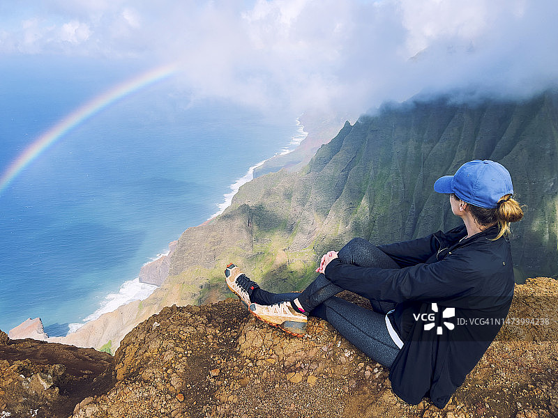 女人看着美国夏威夷考艾岛纳帕利海岸上空的彩虹图片素材