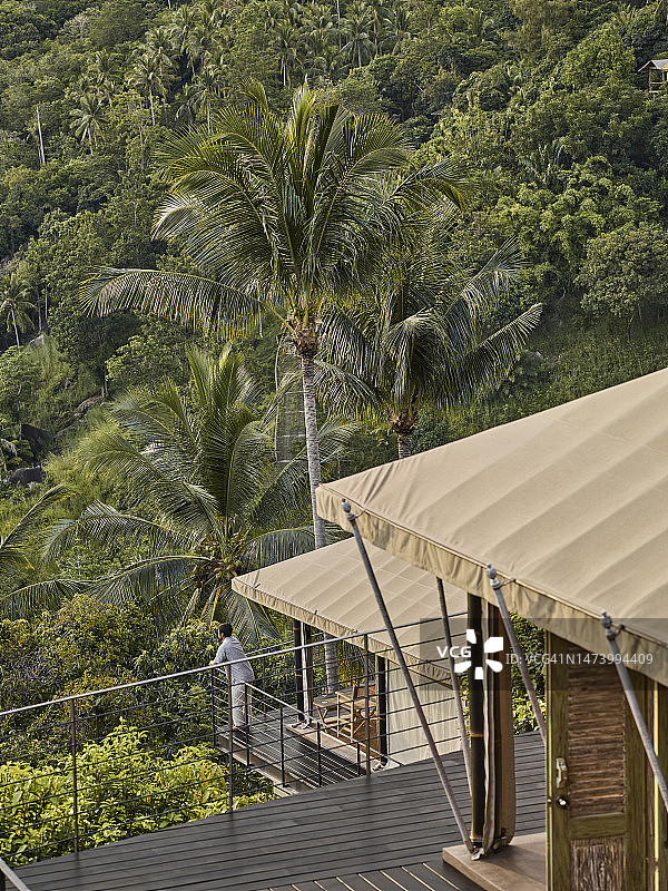 男游客在豪华生态野营度假村的帐篷别墅平台上放松身心，欣赏美景。图片素材