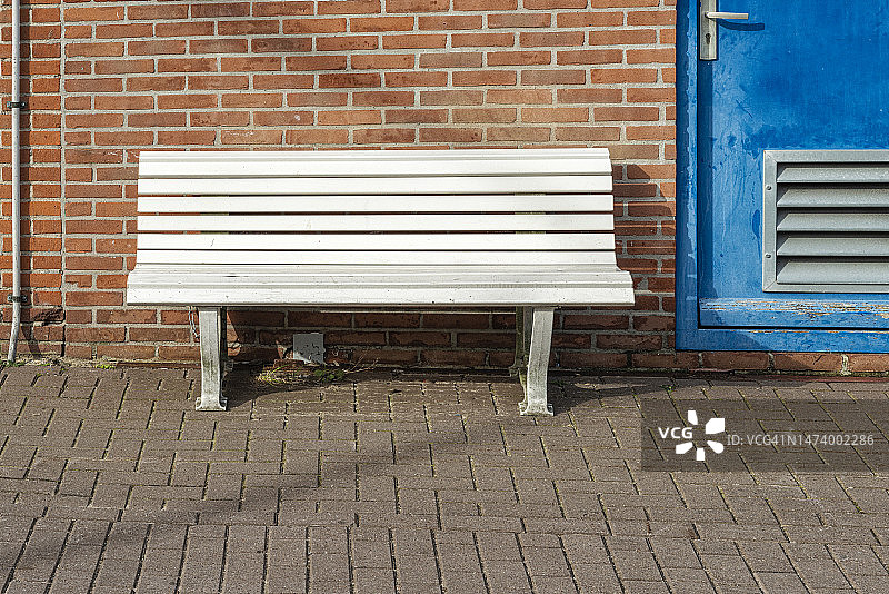 靠在石墙边的白色塑料长凳图片素材