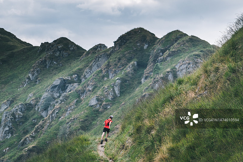 越野跑者穿过高山草甸，攀登山路图片素材