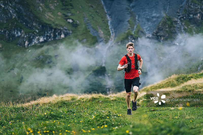 越野跑者穿过高山草甸，攀登山路图片素材
