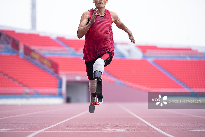 在体育场使用假肢的残疾男跑步者图片素材