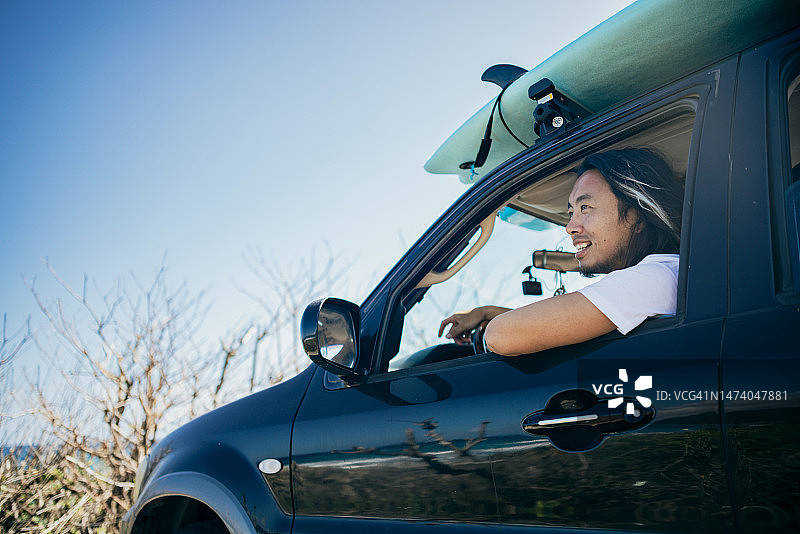 亚洲冲浪爱好者驱车前往冲浪目的地，旅途中愉快地聊天，准备迎接激动人心的冲浪体验图片素材