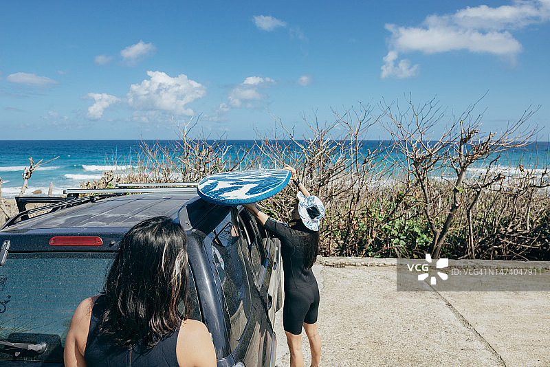 亚洲冲浪爱好者从车上卸下冲浪设备，准备前往海滩享受冲浪的刺激图片素材