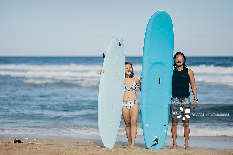 两名冲浪者站在海滩上，手持冲浪板微笑图片素材