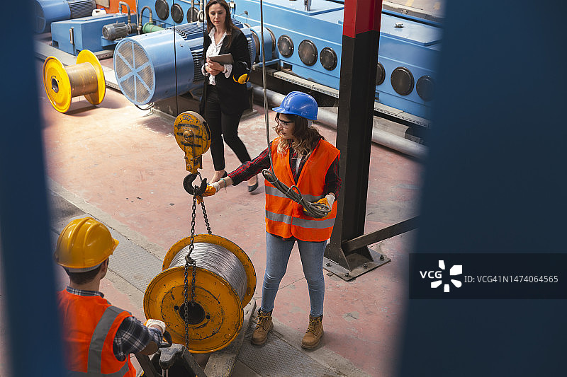 年轻产业工人在操作起重机时手持遥控器图片素材