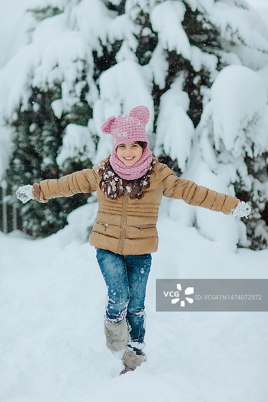 穿着粉色外套的女孩在雪地里玩耍图片素材