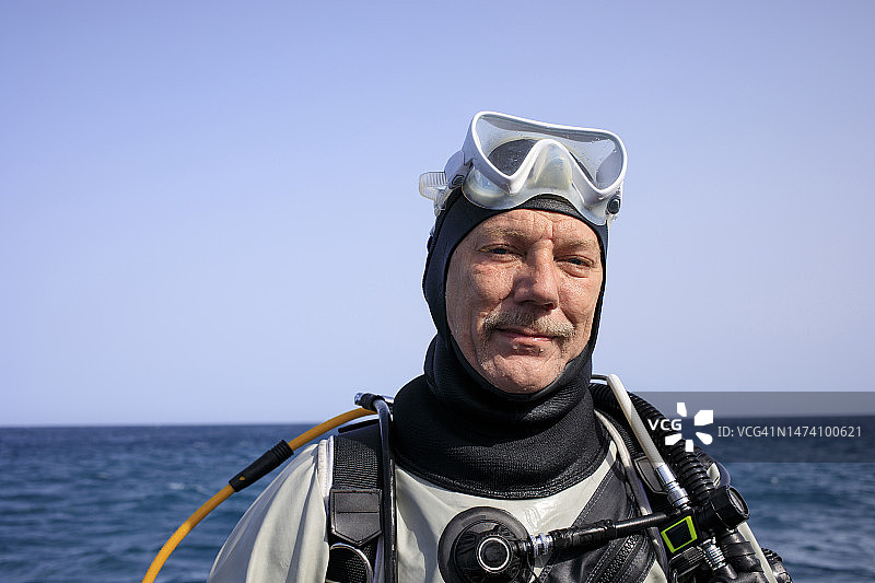 快乐的中老年英俊男潜水员在水肺潜水后，在美丽的热带蓝色海洋和珊瑚礁背景下进行水上运动图片素材