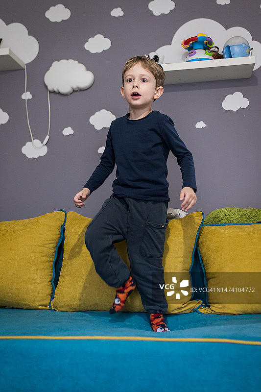 可爱的小男孩在沙发上跳跃图片素材