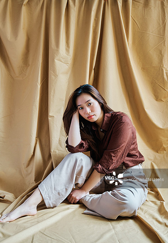 坐在悬挂布前的女人图片素材